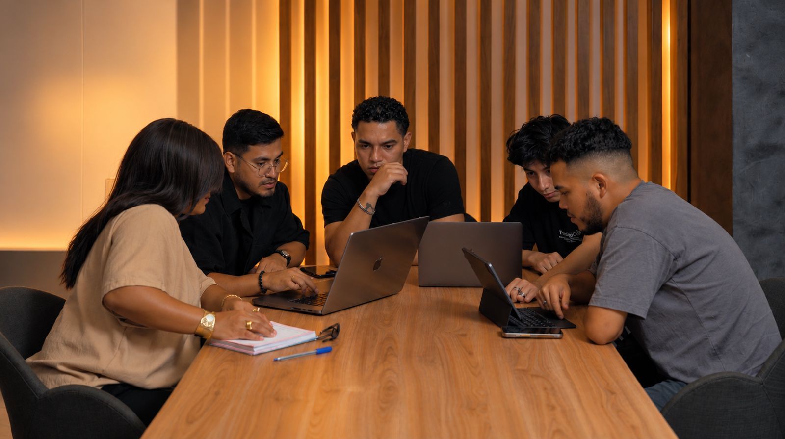 Cinco integrantes del equipo de VOLTA revisan una campaña alrededor de una mesa, con laptops y una libreta.